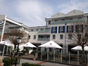 un edificio con sombrillas blancas delante en Komfortapartment Zingster-Meerblick, en Zingst