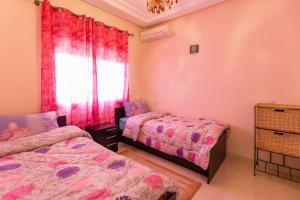 een slaapkamer met 2 bedden en een raam bij Résidence Bab El Janoub in Ouarzazate