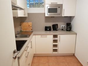 eine kleine Küche mit weißen Schränken und einer Mikrowelle in der Unterkunft Apartments Haupt in Kobern-Gondorf