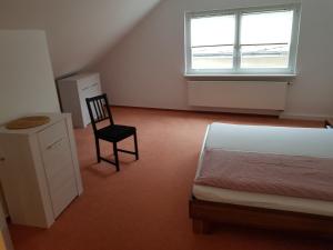 ein Schlafzimmer mit einem Bett, einem Stuhl und einem Fenster in der Unterkunft Apartments Haupt in Kobern-Gondorf