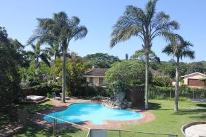 a swimming pool in the yard of a house with palm trees at Laudin's View in Umtentweni