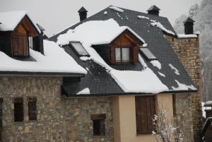 una casa con nieve en el techo en APARTAMENTOS LÁZARO-Calle Iglesia 8 - 1º C en Escarrilla