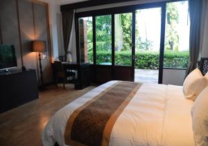 1 dormitorio con 1 cama grande y puerta corredera de cristal en Tukonnee Villas Koh Yao Noi, en Ko Yao Noi