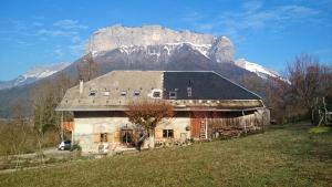 an old house with a mountain in the background at Ferme familiale chez Lili in Alex