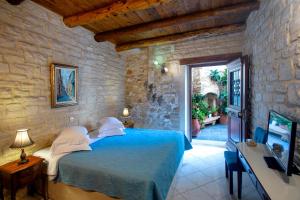 a bedroom with a blue bed in a stone wall at Casa Moazzo Suites and Apartments in Rethymno Town