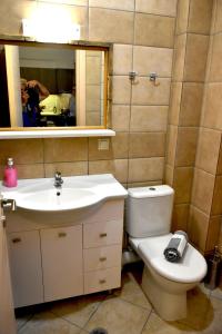 a bathroom with a sink and a toilet and a mirror at Mersina Apartments in Keri