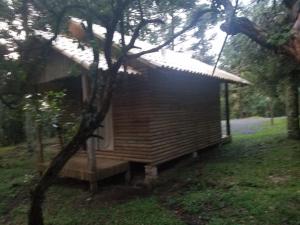 uma pequena cabana de madeira com um alpendre numa floresta em Pousada Serra Catarinense em São Joaquim