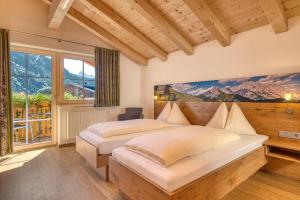 a bedroom with two beds and a large window at Landhotel Kirchenwirt in Unken