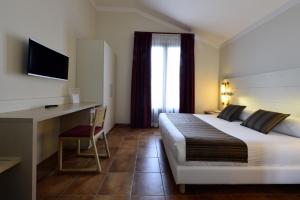 um quarto de hotel com uma cama grande e uma secretária em Hotel Parco Degli Aromi Resort & SPA em Valderice