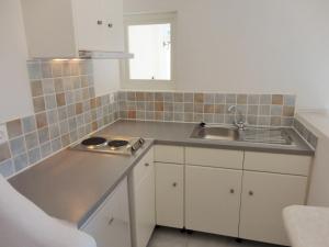 una cocina con armarios blancos y fregadero en Meltemi Studios and Apartments en Logaras