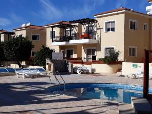 a villa with a swimming pool in front of a building at Sirena Sunrise Prestige apartments in Paphos City