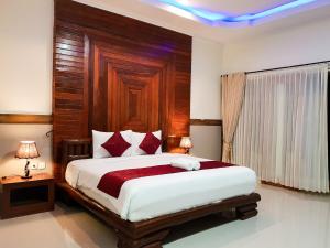 ein Schlafzimmer mit einem großen Bett mit einem hölzernen Kopfteil in der Unterkunft Ogix Cliff Paradise in Nusa Penida