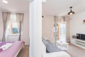 ein Schlafzimmer mit einer Couch und einem Fernseher in einem Zimmer in der Unterkunft Apartmani Antiqua in Živogošće