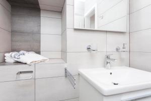 ein weißes Badezimmer mit Waschbecken und Spiegel in der Unterkunft Apartmani Antiqua in Živogošće + 37 Fotos