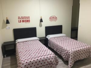 2 camas en una habitación con sábanas rojas y blancas en JQC Rooms, en Madrid