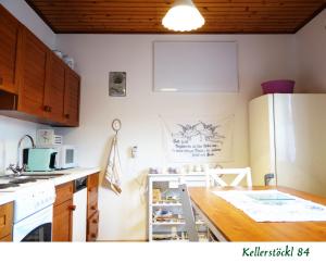 uma cozinha com um frigorífico branco e uma mesa de madeira em Kellerstöckl 84 em Moschendorf