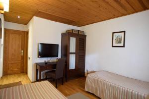- une chambre avec un bureau, un lit et une télévision dans l'établissement Hotel Els Puis, à Esterri d'Àneu