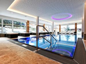 a swimming pool in a hotel lobby with a purple ceiling at Hotel Theresia in Ramsau im Zillertal