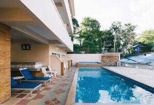 a swimming pool with blue chairs next to a house at Kata Sun Beach Hotel in Kata Beach