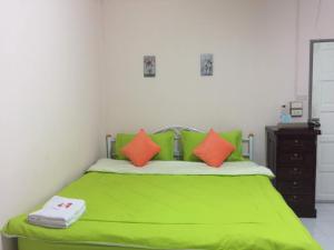 ein Schlafzimmer mit einem grünen Bett und orangefarbenen Kissen in der Unterkunft Baanpak Jomyutt Suan Phueng in Suan Phung