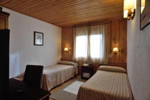 
a hotel room with two beds and two lamps at Hotel Els Puis in Esterri d'Àneu
