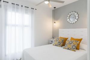 コラレホにあるApartment Urban Chill BBQ Corralejo By Holidays Homeの白いベッドと壁に時計が備わるベッドルーム1室が備わります。