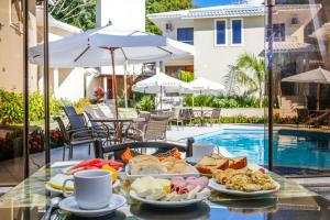 a tray of food on a table next to a pool at Portal Ville - Rede Soberano in Porto Seguro