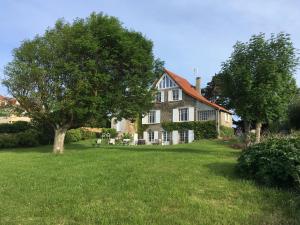 a large house with a tree in the yard at Chambres d'hôtes Les 4 Vents Pointe du Hoc - Landing Beaches in Grandcamp-Maisy