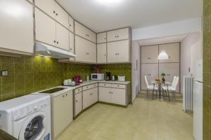 a kitchen with white cabinets and a washer and dryer at Tranquil Central Apt, behind Athens Caravel Area in Athens +32 photos