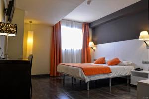 ein Schlafzimmer mit einem Bett mit einer orangefarbenen Decke in der Unterkunft Hotel Can Batiste in Sant Carles de la Ràpita