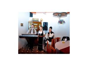 three people standing in a room with a table at Pensiunea Andrei Sibiel in Sibiel