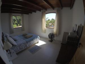 a bedroom with a bed and two windows at Residencial Flor De Ipê in Paraty