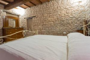 1 dormitorio con cama y pared de piedra en Villa Costanzi: Beautiful Rural Apartment!, en Sigillo