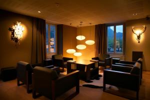 una sala de espera con sillas, mesas y una lámpara de araña en Victoria - Alpine Boutique Hotel & Fine Dining en Meiringen