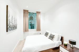 a white bedroom with a bed and a window at Terlon Apartments in Liverpool