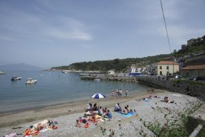 a group of people on a beach near the water at Hotel Baia Di Puolo in Massa Lubrense
