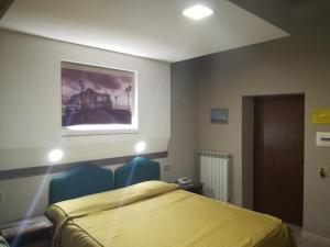 a bedroom with a bed and two blue chairs at Hotel Lento in Melito di Napoli