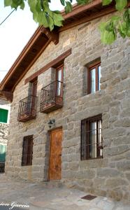 a stone building with windows and a wooden door at El Mirador del Alberche 1 in Navaluenga