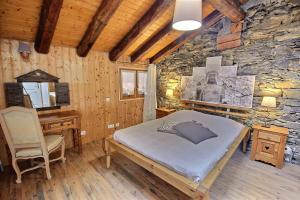 a bedroom with a bed in a stone wall at Les Balcons du Molliebon in Séez