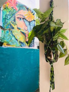 a plant in front of a painting of a woman with butterflies at Mahalo Hostel in Abraão