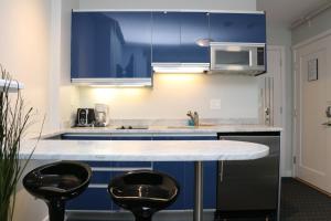 a kitchen with blue cabinets and two bar stools at Stylish Studio on Newbury Street, #10 in Boston