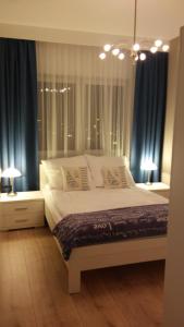 a bedroom with a large bed with blue curtains at PANORAMA KOSZALIN in Koszalin