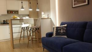 a living room with a blue couch and a kitchen at PANORAMA KOSZALIN in Koszalin