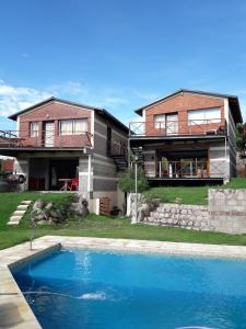 a house with a swimming pool in front of a house at Cabañas Doña Itati in Villa Carlos Paz