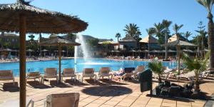 una piscina en un complejo con sillas y una fuente en Fuerteventura House Wifi -, en Corralejo