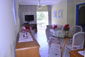 uma sala de estar com uma mesa e um sofá em Ap Enseada Lado Praia Ar Cond Piscina Wi-Fi 500Mb no Guarujá