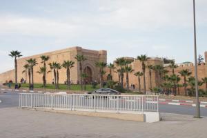 a building with palm trees in front of a street at Riad Razoli Sidi Daoui in Rabat