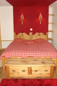 - une chambre avec un lit en bois et un mur rouge dans l'établissement Auberge de la poste, aux Diablerets