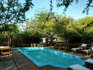 a swimming pool in a yard with benches and trees at Cabañas Lignum - Tiny House in La Granja