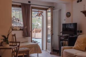 a living room with a tv and a sliding glass door at Baita de Eliseo B&B in Valdisotto